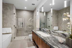 Bathroom featuring tile walls, vanity, a freestanding bath, light tile patterned flooring, and walk in shower