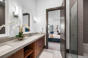 Bathroom with double vanity, a tile shower, ensuite bathroom, and light wood-style flooring