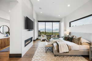 Bedroom with hardwood / wood-style floors, lofted ceiling, recessed lighting, and a fireplace