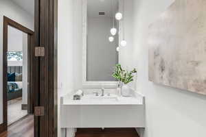 Ensuite bathroom featuring vanity and dark wood-type flooring