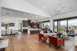 Living room featuring a chandelier, recessed lighting, light wood-type flooring, and high vaulted ceiling