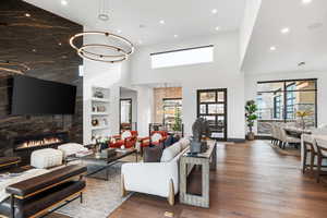 Living area featuring a chandelier, dark wood-type flooring, a high end fireplace, recessed lighting, and built in shelves