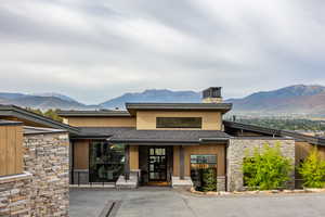Entrance to property featuring stone siding, a mountain view, and roof with shingles