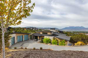 View of front of home featuring stone siding, a garage, concrete driveway, and a mountain view