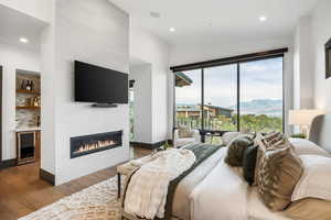 Bedroom with access to exterior, wood finished floors, wine cooler, vaulted ceiling, and recessed lighting