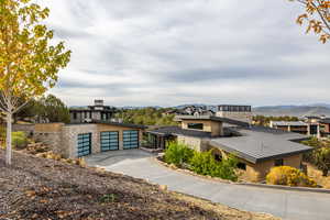 Contemporary house featuring stone siding, a mountain view, concrete driveway, a garage, and a standing seam roof