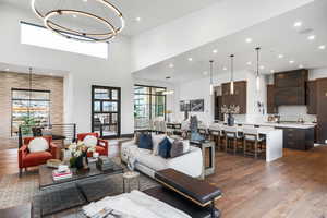 Living room featuring a chandelier, dark wood-type flooring, recessed lighting, and a towering ceiling