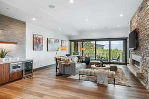 Living area with light wood-style floors, recessed lighting, wine cooler, and a stone fireplace