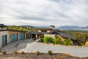 View of front of home with stone siding, a mountain view, and driveway