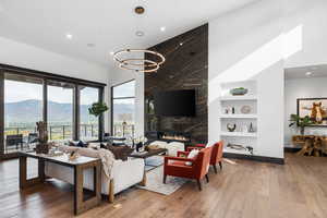 Living room with a fireplace, light wood-style floors, recessed lighting, built in features, and a chandelier