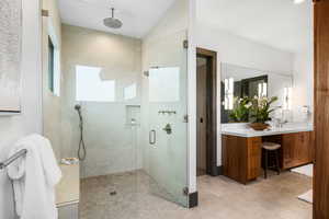 Bathroom with a shower stall, double vanity, and healthy amount of natural light