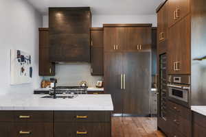 Kitchen with ventilation hood, decorative backsplash, oven, light wood-style floors, and modern cabinets
