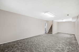 Finished basement featuring stairs, carpet floors, and a textured ceiling