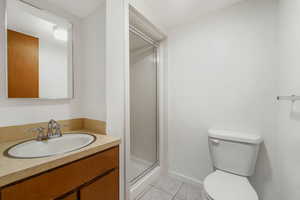 Bathroom with light tile patterned floors, vanity, and a shower stall