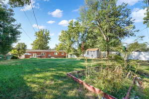View of green lawn featuring a shed