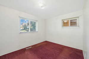 Spare room with dark colored carpet and baseboards