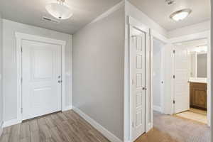 Hallway with a textured ceiling and light wood-type flooring