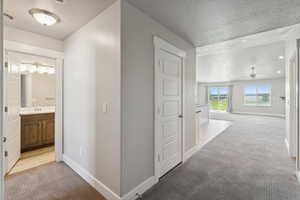 Hallway featuring light colored carpet, a textured ceiling, and recessed lighting