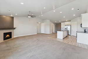 Kitchen featuring open floor plan, light colored carpet, white cabinetry, recessed lighting, and dark countertops