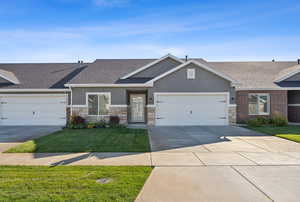 View of front of home featuring roof with shingles, a front yard, stucco siding, stone siding, and driveway