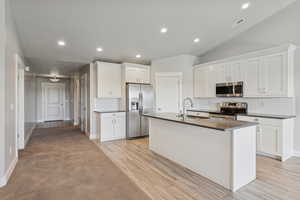 Kitchen featuring white cabinetry, appliances with stainless steel finishes, tasteful backsplash, recessed lighting, and an island with sink