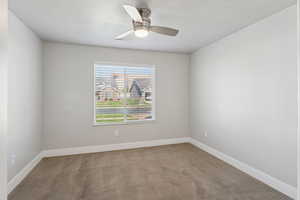 Carpeted spare room featuring ceiling fan and a textured ceiling
