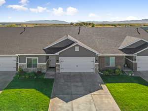 View of front facade featuring roof with shingles, a front lawn, and a mountain view