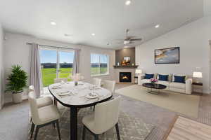 Carpeted dining room featuring a glass covered fireplace, recessed lighting, lofted ceiling, and a ceiling fan