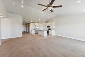 Unfurnished living room featuring light colored carpet, recessed lighting, vaulted ceiling, and ceiling fan