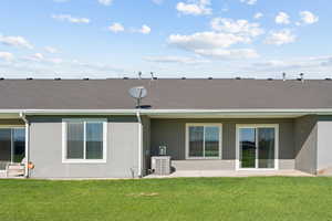 Rear view of property with stucco siding, a patio area, and a yard