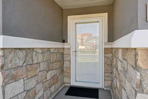 Doorway to property with stone siding and stucco siding