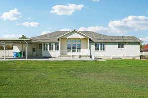 Back of property with a patio, a yard, and a shingled roof