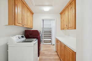 Washroom featuring cabinet space, light wood finished floors, and independent washer and dryer