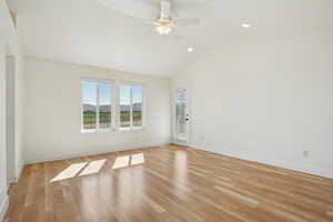 Empty room featuring light wood-style flooring, vaulted ceiling, a mountain view, a ceiling fan, and recessed lighting