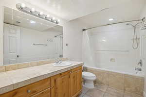 Full bathroom featuring tiled shower / bath, vanity, light tile patterned floors, a textured ceiling, and recessed lighting