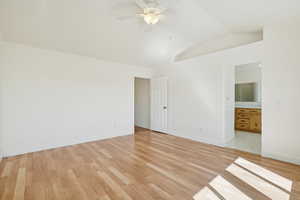 Unfurnished bedroom with light wood finished floors, lofted ceiling, a ceiling fan, and ensuite bath