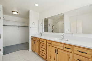 Full bathroom featuring a shower stall, a spacious closet, double vanity, recessed lighting, and light marble finish floors