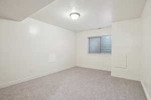 Unfurnished room with a textured ceiling and light carpet