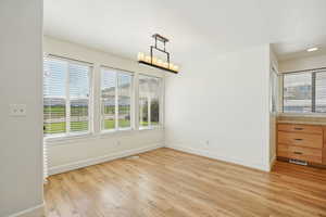 Unfurnished dining area featuring light wood-type flooring and a chandelier