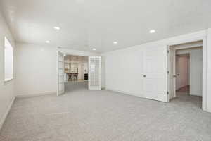 Unfurnished living room featuring french doors, light carpet, recessed lighting, and a textured ceiling