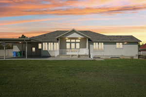Rear view of property with a patio area, a lawn, and a shingled roof