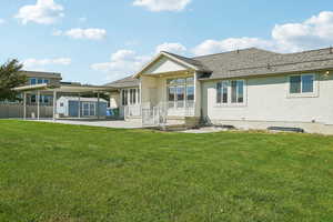 Rear view of house with a patio, stucco siding, a shingled roof, and a storage unit