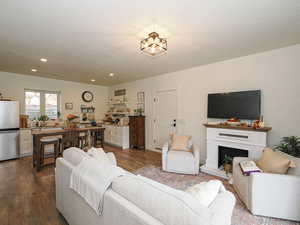 Living area with wood-type flooring, a textured ceiling, recessed lighting, and a fireplace with raised hearth