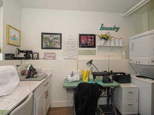 Office space featuring stacked washer and clothes dryer and dark wood-type flooring