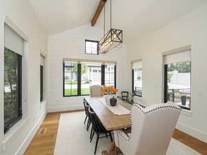 Dining area with beamed ceiling, wood finished floors, a chandelier, high vaulted ceiling, and wooden walls