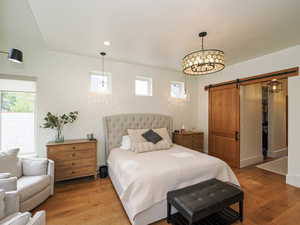 Bedroom with a barn door, wood finished floors, a chandelier, and recessed lighting