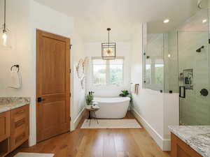 Full bathroom with vanity, a shower stall, light wood-style floors, a freestanding tub, and recessed lighting