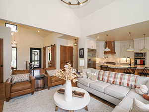 Living room featuring a barn door, high vaulted ceiling, a chandelier, wood finished floors, and recessed lighting