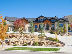 View of front of house featuring stone siding, covered porch, and concrete driveway