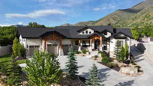 View of front of house with stone siding, concrete driveway, an attached garage, a mountain view, and a chimney